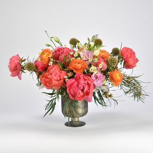 Coral peonies and orange ranunculus in vintage patina urn by best florist Raleigh