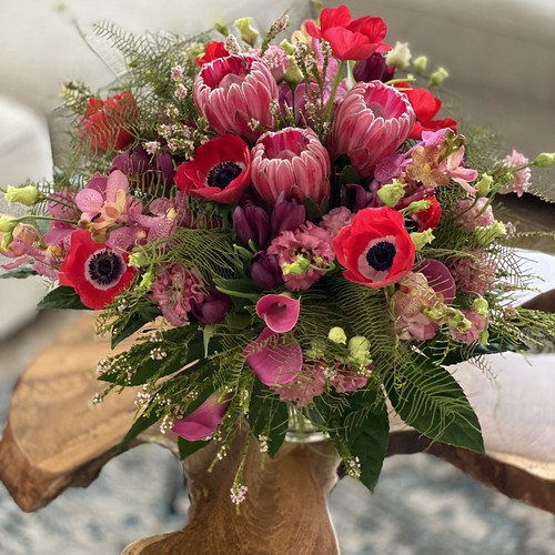 Red anemones and pink protea with calla lilies in glass vase for flower delivery Raleigh