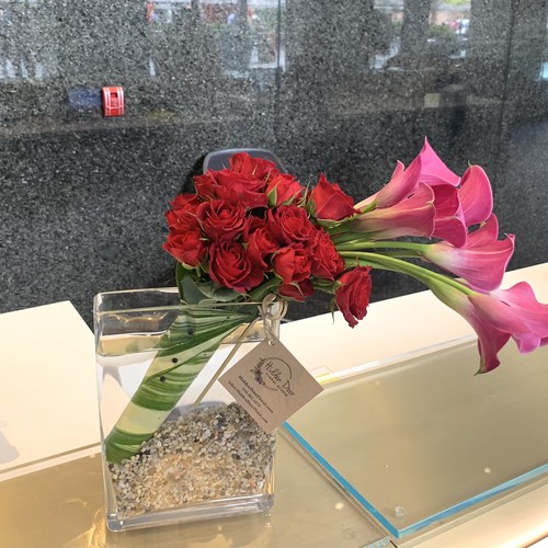 Red roses and pink calla lilies in modern glass vase on marble counter by best florist Raleigh