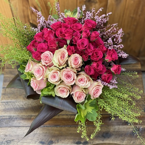 Hot pink and blush roses with heather in tropical leaf wrap from Raleigh flower shop